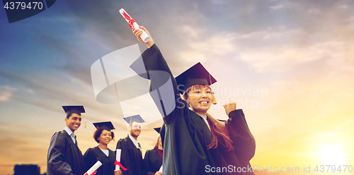 Image of happy students in mortar boards with diplomas