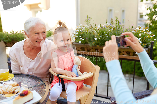 Image of woman photographing her family at cafe