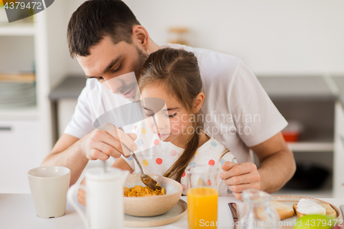 Image of happy family eating flakes for breakfast at home