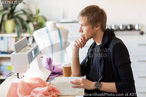 Image of fashion designer reading book at studio