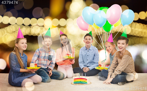 Image of happy children in party hats with birthday cake