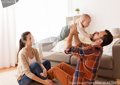 Image of happy mother and father playing with baby at home