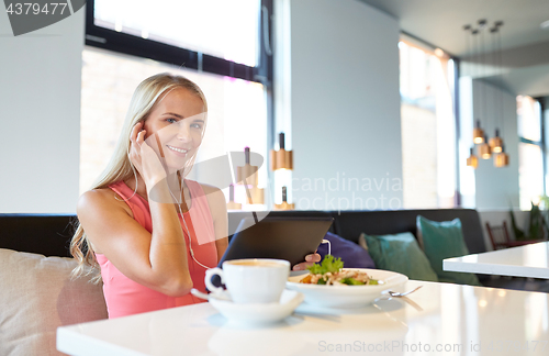 Image of happy young woman with tablet pc at restaurant