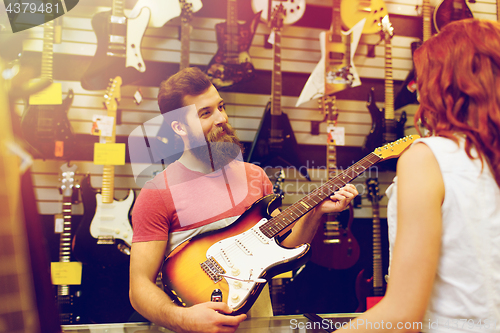 Image of assistant showing customer guitar at music store