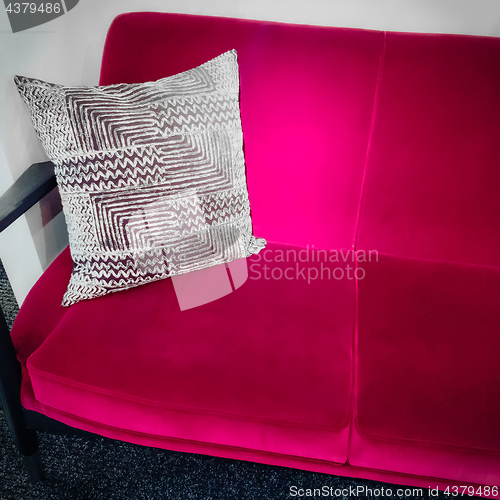 Image of Vibrant pink velvet sofa with ornamental cushion