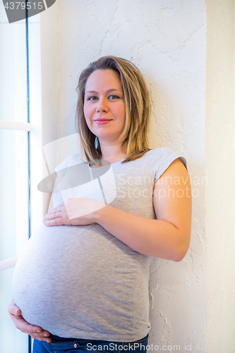 Image of Pregnant woman standing near window