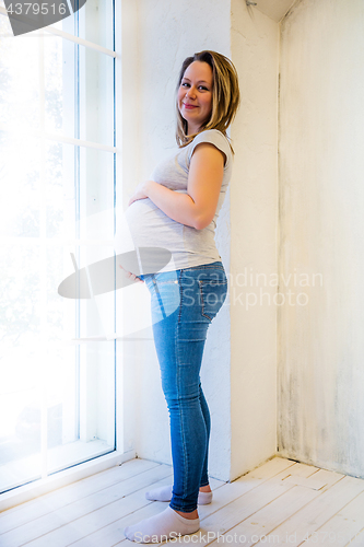 Image of Beautiful pregnant woman standing near window