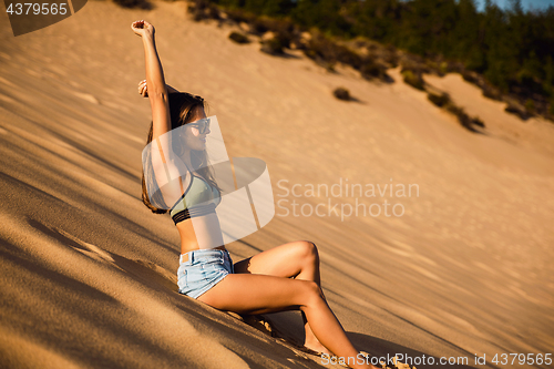 Image of Young girl sitting on a sand dune