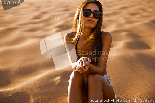 Image of Young girl sitting on a sand dune