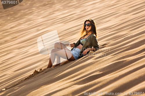 Image of Young girl lying on a sand dune