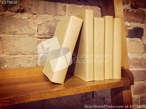 Image of Books on a wooden shelf near a brick wall