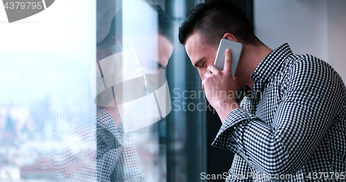 Image of Business Man Talking On Cell Phone, Looking Out Office Window