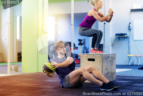 Image of woman and man with medicine ball exercising in gym