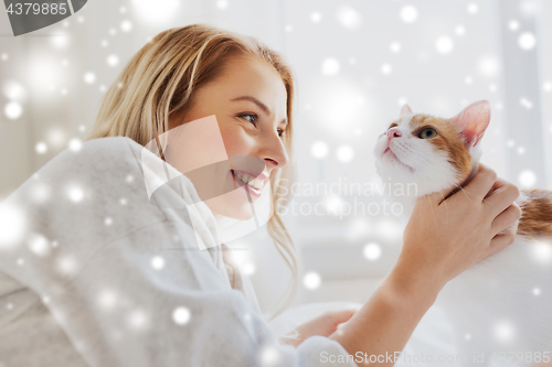 Image of happy young woman with cat in bed at home