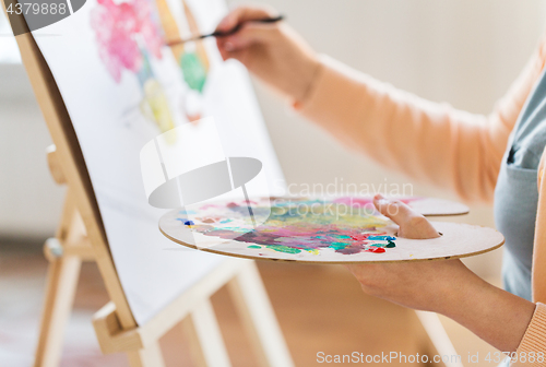 Image of artist with palette and brush painting at studio