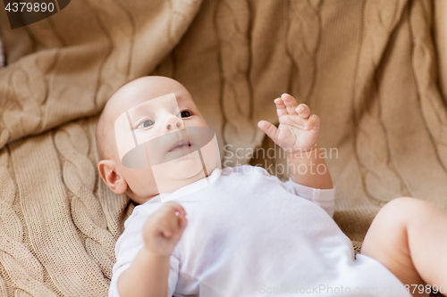 Image of sweet little baby boy lying on knitted blanket