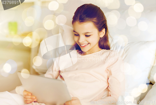 Image of happy girl in bed with tablet pc over lights