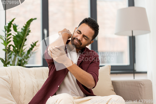 Image of unhappy man suffering from pain in hand at home