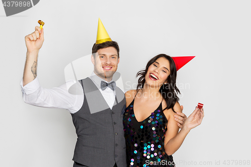 Image of happy couple with party blowers having fun