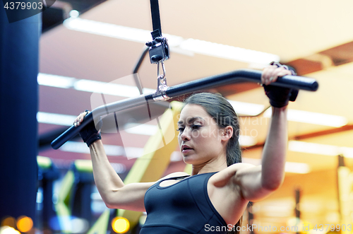 Image of woman flexing arm muscles on cable machine in gym