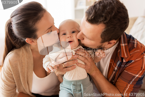 Image of happy mother and father kissing baby at home