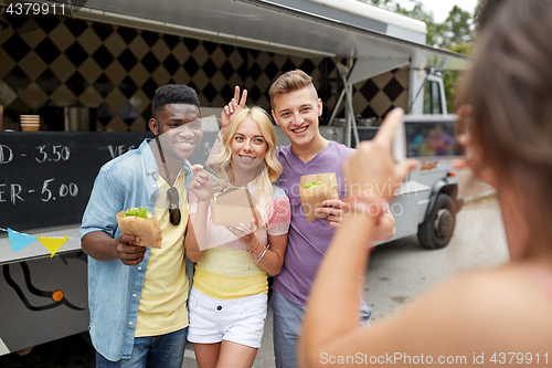 Image of woman photographing friends eating at food truck