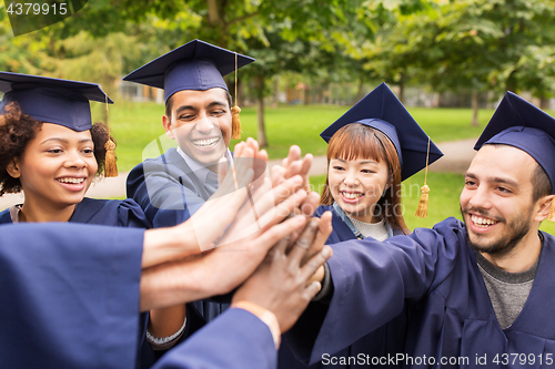 Image of happy students in mortar boards making high five