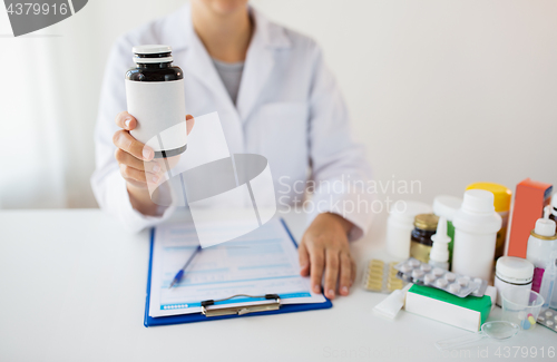 Image of close up of doctor with medicines and clipboard