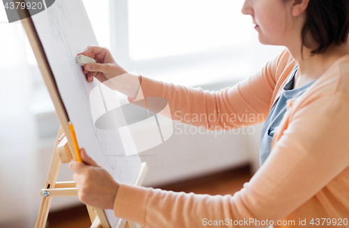 Image of artist with eraser drawing picture at art studio