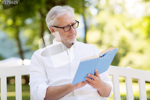 Image of senior man reading book at summer park