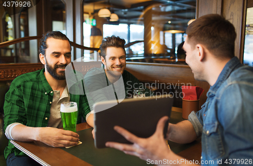 Image of friends with tablet pc and green beer at pub