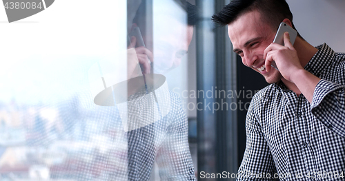 Image of Business Man Talking On Cell Phone, Looking Out Office Window