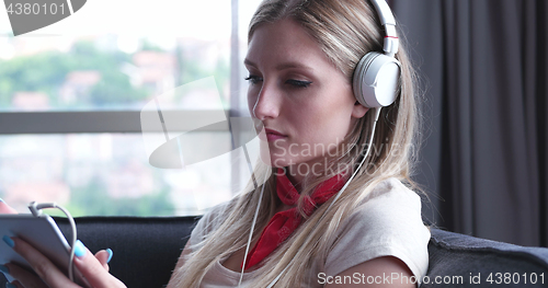 Image of Lovely Blond Woman Listening To Music while resting on couch