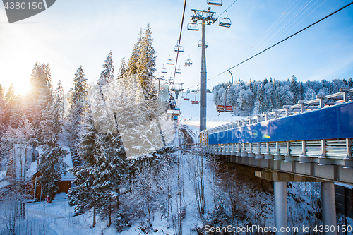 Image of Skiers on the ski lift riding up at ski resort with beautiful background of snow-covered slopes, forests, hills in Bukovel, Ukraine