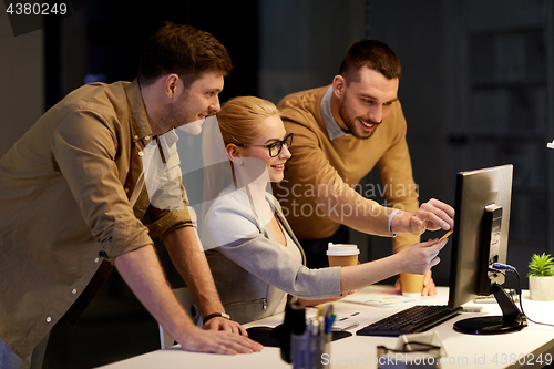 Image of business team with computer working late at office