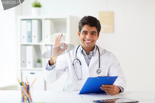 Image of happy doctor with clipboard at clinic showing ok