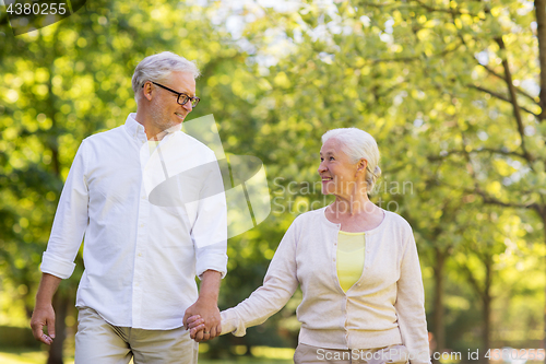 Image of happy senior couple walking at summer park