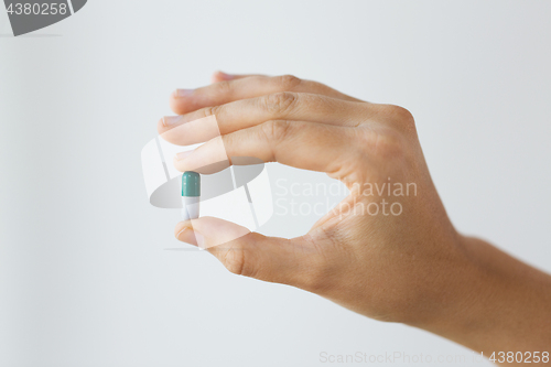 Image of close up of hand holding capsule of medicine