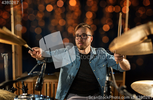 Image of musician playing drum kit at concert over lights