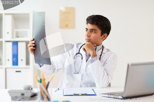 Image of doctor looking at spine x-ray scan at clinic