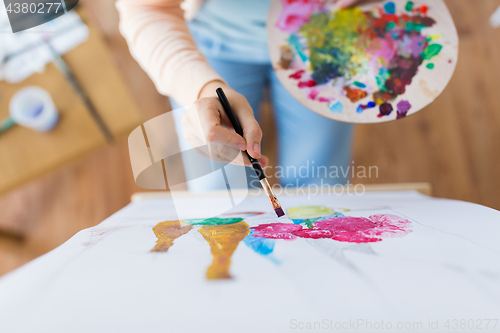 Image of artist with palette and brush painting at studio