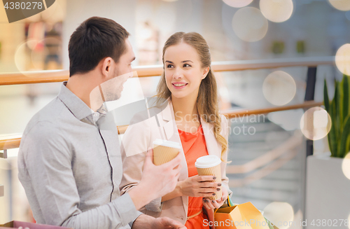 Image of happy couple with shopping bags drinking coffee