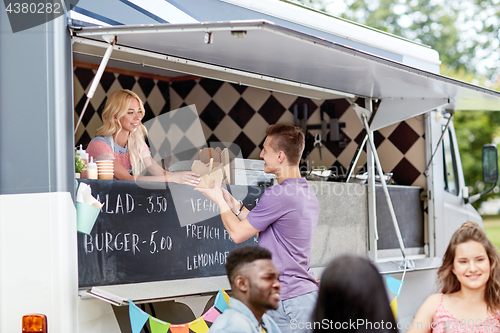 Image of saleswoman at food truck serving male customer