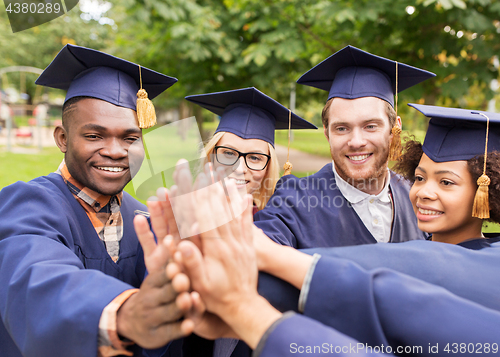 Image of happy students in mortar boards making high five