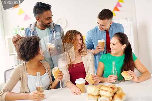 Image of happy friends or team eating at office party