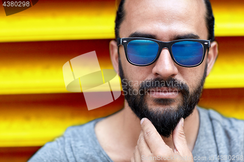 Image of close up of man in sunglasses touching beard