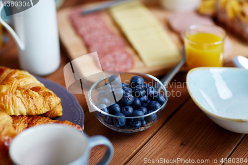 Image of bowl of blueberries on wooden table at breakfast