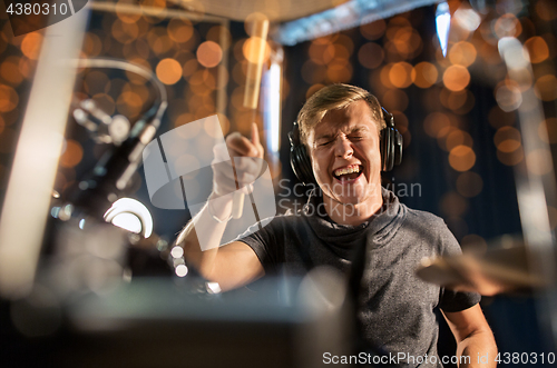 Image of musician playing drum kit at concert over lights