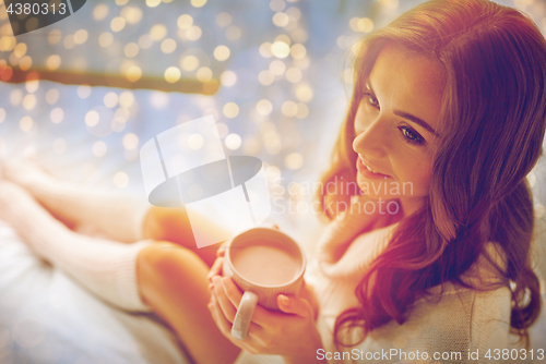 Image of happy woman with cup of cocoa in bed at home