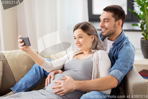 Image of man and pregnant woman taking selfie at home